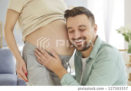 Listening sound in pregnant mother belly, happy future father expecting first baby close caring Listening sound in pregnant mother belly, happy future father expecting first baby close caring 127303357