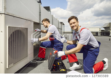 Technician installing air conditioner and looking cheerful at camera showing thumb up sigh. 127303389