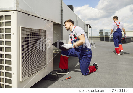 Worker Maintaining Air Conditioning System on Roof 127303391