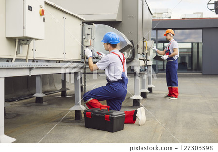 Workers Repairing Or Servicing Hvac And Ventilation Equipment On Roof 127303398