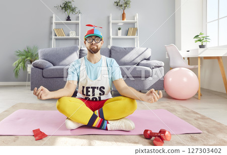 Funny happy sportsman lotus pose doing mind, body meditation, sitting to exercise, playful fitness 127303402