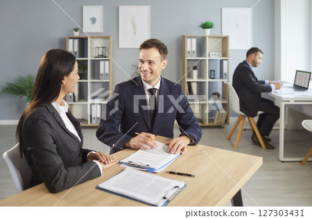 Two business people collaborating on work in office space, discussing project and focusing on tasks. Two business people collaborating on work in office space, discussing project and focusing on tasks. 127303431