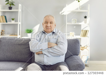 Serious Senior Man Sitting on Sofa at Home 127303448