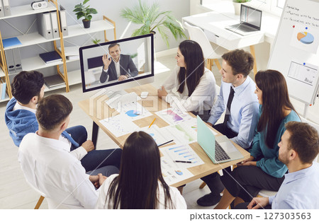Business people having online videoconference in meeting room with man colleague sitting in office Business people having online videoconference in meeting room with man colleague sitting in office 127303563