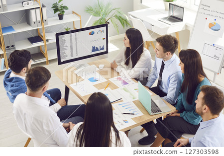 Team of business professionals having work meeting, sitting around table and looking at computer Team of business professionals having work meeting, sitting around table and looking at computer 127303598