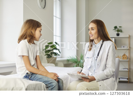 Friendly female pediatrician talking with little boy patient sitting on couch in medical clinic Friendly female pediatrician talking with little boy patient sitting on couch in medical clinic 127303618