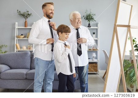 Three generations of men are gathered in front of mirror, each dressed in white shirt and black tie Three generations of men are gathered in front of mirror, each dressed in white shirt and black tie 127303619