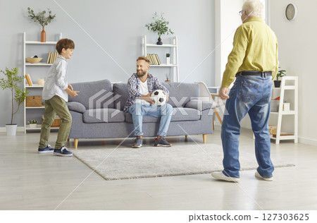 Happy child boy playing football game with senior grandfather and young father at home Happy child boy playing football game with senior grandfather and young father at home 127303625