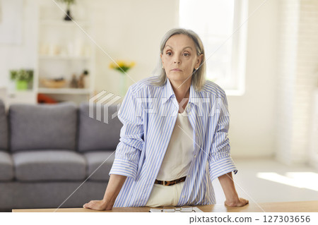 Serious Elderly Woman Standing In Home Office With Focused Expression Serious Elderly Woman Standing In Home Office With Focused Expression 127303656