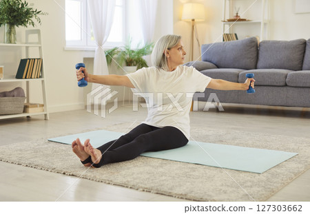 Senior Woman Exercising With Dumbbells In A Home Workout Routine Senior Woman Exercising With Dumbbells In A Home Workout Routine 127303662