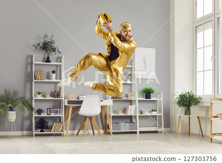 Funny young man holding gold bar having fun in living room at home celebrating success Funny young man holding gold bar having fun in living room at home celebrating success 127303756
