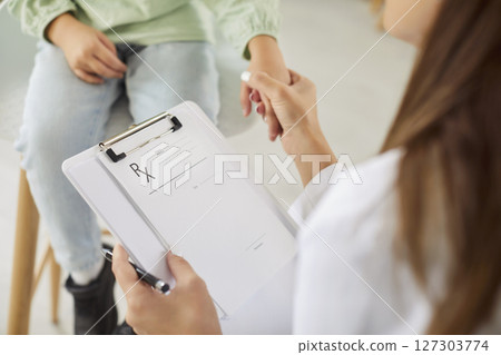 Friendly doctor holding hands with preschool girl during checkup with care and support in clinic. Friendly doctor holding hands with preschool girl during checkup with care and support in clinic. 127303774