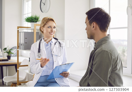 Happy young doctor, female general practitioner showing health test result on clipboard to patient Happy young doctor, female general practitioner showing health test result on clipboard to patient 127303904
