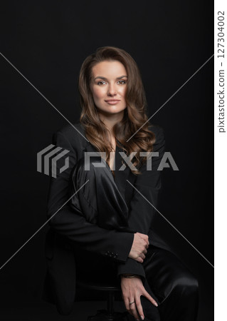 Beautiful woman with dark suit and wavy hair studio portrait 127304002