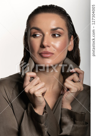 Beautiful woman with trench coat and wet hair studio portrait 127304005