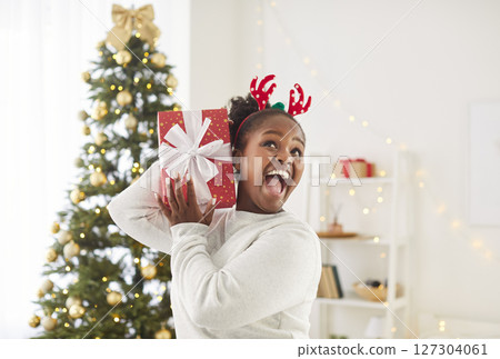 Portrait of excited young happy woman holding red present gift box standing at home Portrait of excited young happy woman holding red present gift box standing at home 127304061