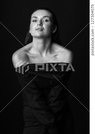Seductive looking woman with dark clothes and wet hair studio portrait 127304070