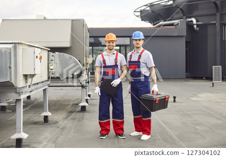 Portrait Of Smiling Workers Servicing Climate Systems On Roof Portrait Of Smiling Workers Servicing Climate Systems On Roof 127304102