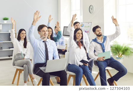 Business people at the conference raising hands voting in the office. 127304103