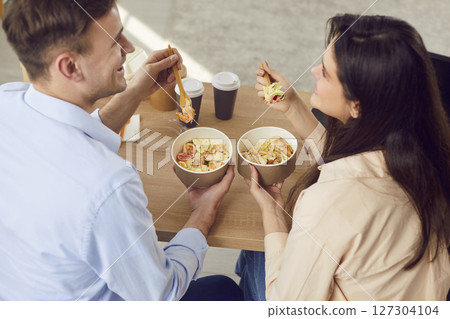 Happy young man and woman are talking happily while enjoying delicious takeaway. 127304104