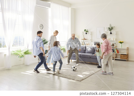 Active sporty happy funny family, three generation people, excited playing football at home 127304114