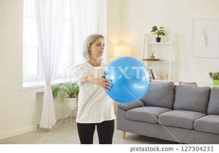 Senior Woman Exercising with Fitball for Home Fitness Training Senior Woman Exercising with Fitball for Home Fitness Training 127304231