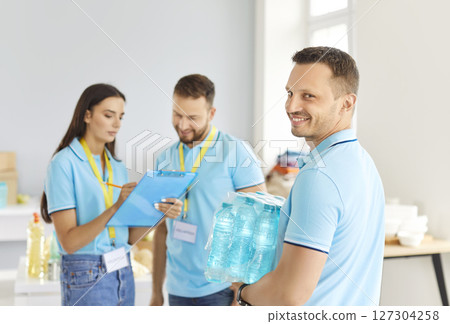 Group of young cheerful volunteers preparing free meal in food bank for donation to people in need. Group of young cheerful volunteers preparing free meal in food bank for donation to people in need. 127304258