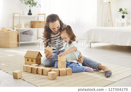 Young happy mother playing game with educational wooden pyramid with little child girl at home Young happy mother playing game with educational wooden pyramid with little child girl at home 127304270