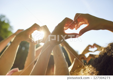 Group of people making heart shape gesture from hands standing in the summer park at sunset. Group of people making heart shape gesture from hands standing in the summer park at sunset. 127304273