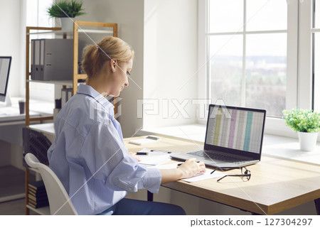 Woman Working with Laptop and Documents in Office 127304297