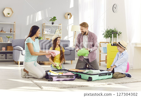 Happy family packing suitcases preparing for summer vacation trip sitting on floor at home. Happy family packing suitcases preparing for summer vacation trip sitting on floor at home. 127304302