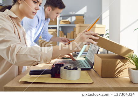 Woman working in logistics center with male colleague preparing order for client in warehouse Woman working in logistics center with male colleague preparing order for client in warehouse 127304324