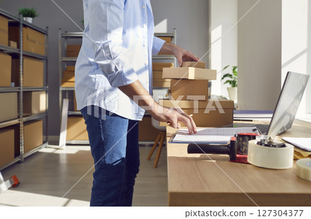 Man Conducting Inventory At Online Shop Warehouse Or Postal Office Man Conducting Inventory At Online Shop Warehouse Or Postal Office 127304377
