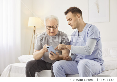 Senior retirement house old resident, young brother helping use smartphone, nursing for help 127304438