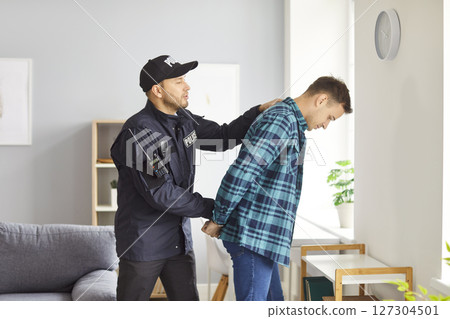 Police Officer Arresting Male Suspect And Putting On Handcuffs 127304501