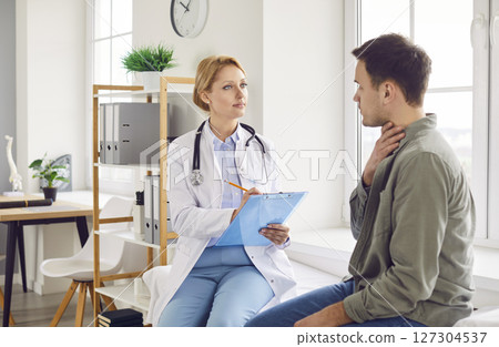 Doctor physician listening to patient complaints about sore throat and cough in medical clinic. 127304537