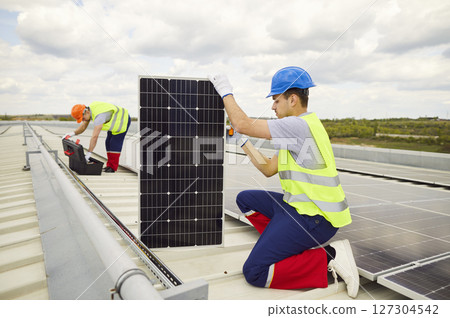 Electrician On Roof Installing Or Maintaining Solar Panels Electrician On Roof Installing Or Maintaining Solar Panels 127304542