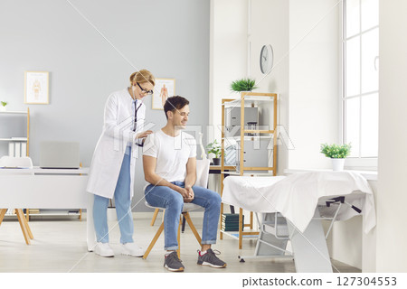 Doctor with stethoscope listening back to heart, lungs, male health care, female doctor clinic  127304553