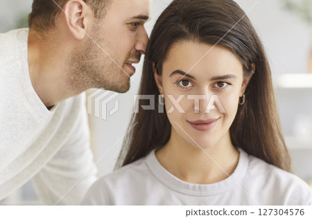 Close up man whispering something in the ear of woman telling her secret or gossip sharing news Close up man whispering something in the ear of woman telling her secret or gossip sharing news 127304576