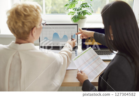 Back View Of Coworkers Using Laptop And Charts In Office 127304582