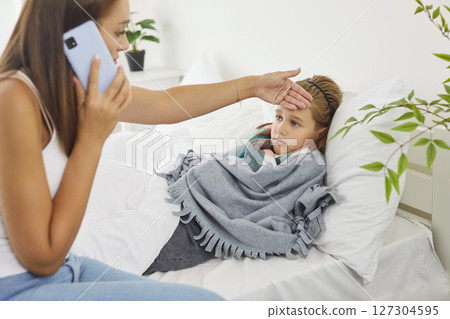 Mother calling to family doctor checking temperature of sick child at home suffering from flu Mother calling to family doctor checking temperature of sick child at home suffering from flu 127304595