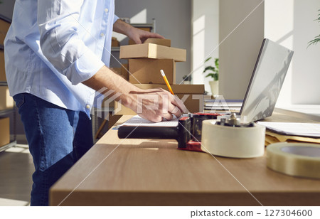 Man working in warehouse checking stock and inventory standing on workplace in storeroom. Man working in warehouse checking stock and inventory standing on workplace in storeroom. 127304600