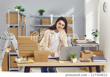 Happy young business woman and logistic manager is working in her small warehouse 127304612