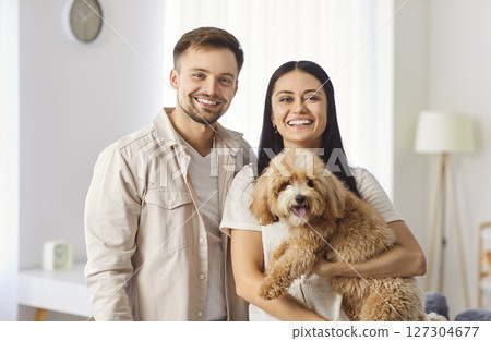Portrait Of Happy Family Couple Holding Dog Together At Home Portrait Of Happy Family Couple Holding Dog Together At Home 127304677