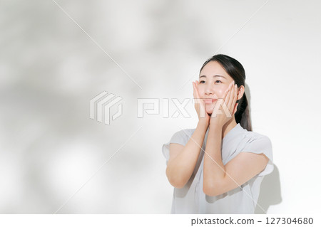 一位二十多歲的女性正在進行夏季皮膚護理 一位二十多歲的女性正在進行夏季皮膚護理 127304680