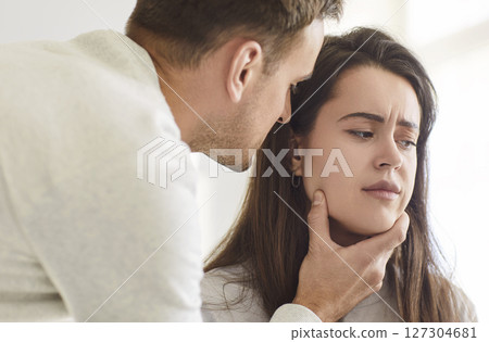 Upset young woman listening her annoyed husband touching her face. Domestic violence concept. Upset young woman listening her annoyed husband touching her face. Domestic violence concept. 127304681