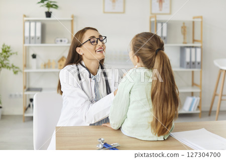 Doctor Pediatrician Talking To Girl Patient In Clinic Office During Appointment Doctor Pediatrician Talking To Girl Patient In Clinic Office During Appointment 127304700