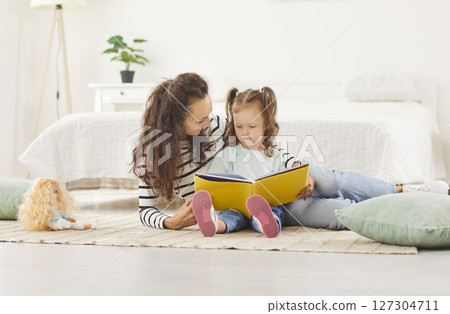Happy smiling mother and baby daughter, babysitter nanny enjoy book story reading, friendly family Happy smiling mother and baby daughter, babysitter nanny enjoy book story reading, friendly family 127304711