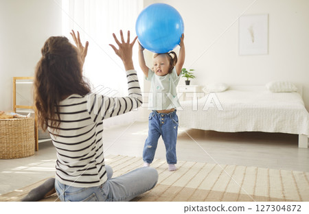 Child girl playing game with a ball with mother in the living room at home together Child girl playing game with a ball with mother in the living room at home together 127304872