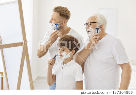 Grandfather, father and little son pretend to shave with cream on their faces, showing family bond. Grandfather, father and little son pretend to shave with cream on their faces, showing family bond. 127304896
